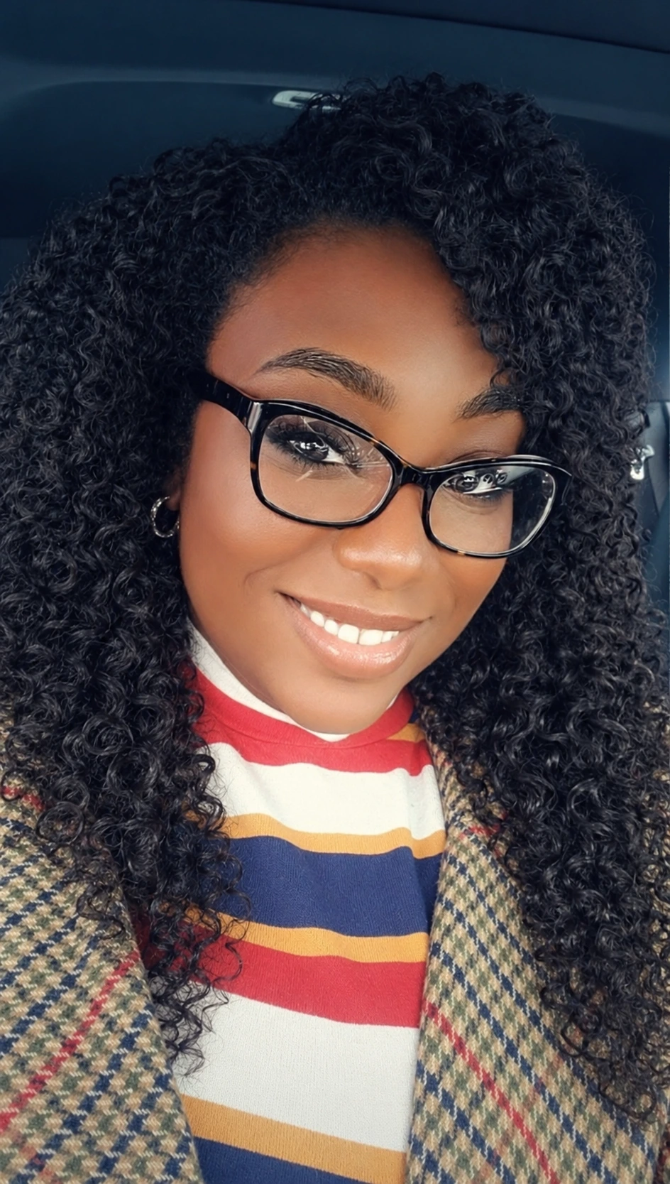 Ivori Rayale smiling, wearing glasses with long black curls